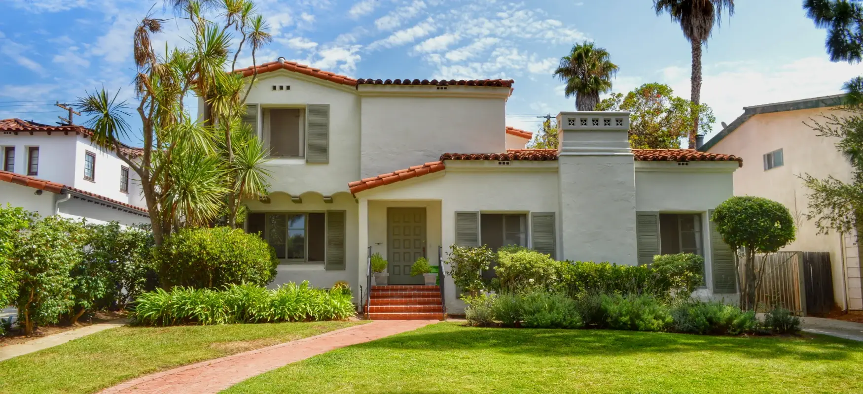 A Spanish-style San Diego home with a tile roof and mature front garden
